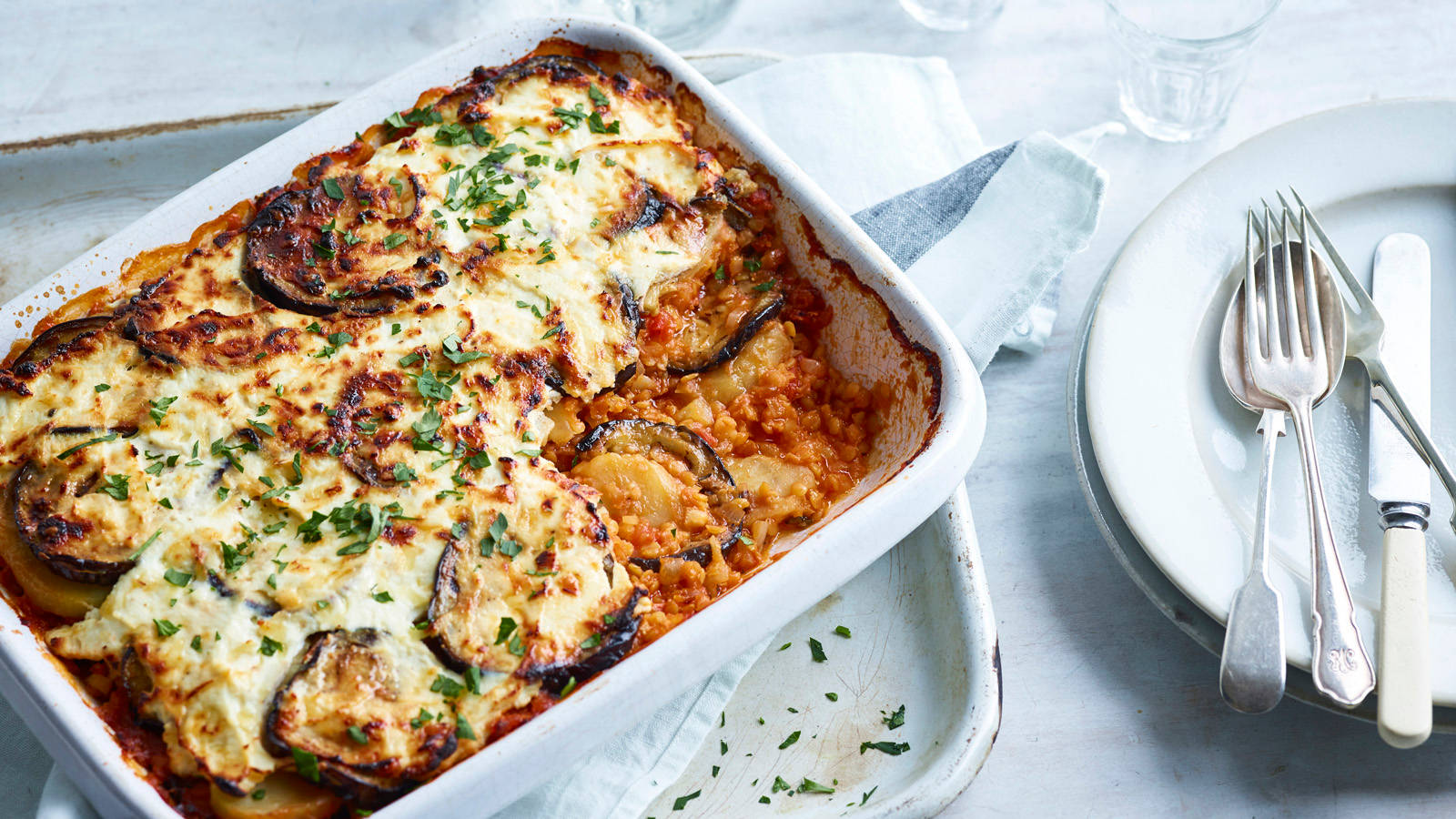 Tray Of Moussaka Near The Plates With Cutlery Background