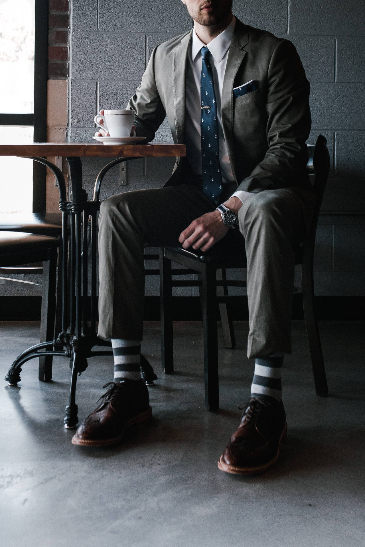 Trendy Man In Stylish Attire Posing At A Café Background