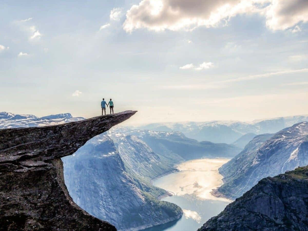 Trolltunga With Two People Holding Hands Background