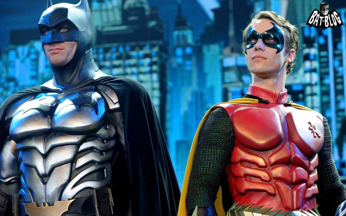 Two Batman And Robin Costumes Standing Next To Each Other Background