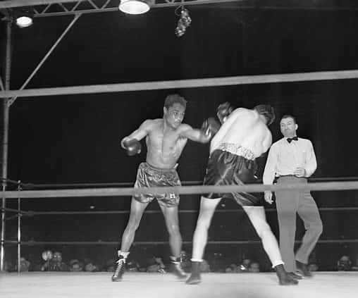 Two Boxers In A Ring With A Referee Background