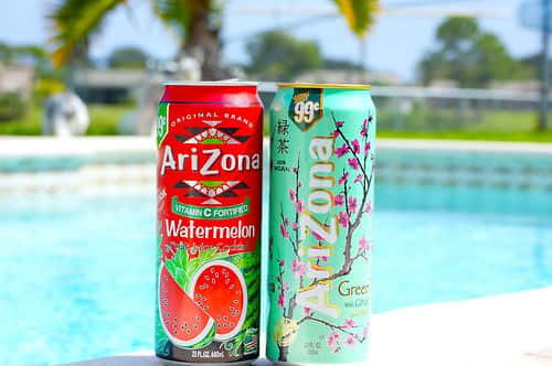 Two Cans Of Watermelon And Watermelon Soda Next To A Pool Background