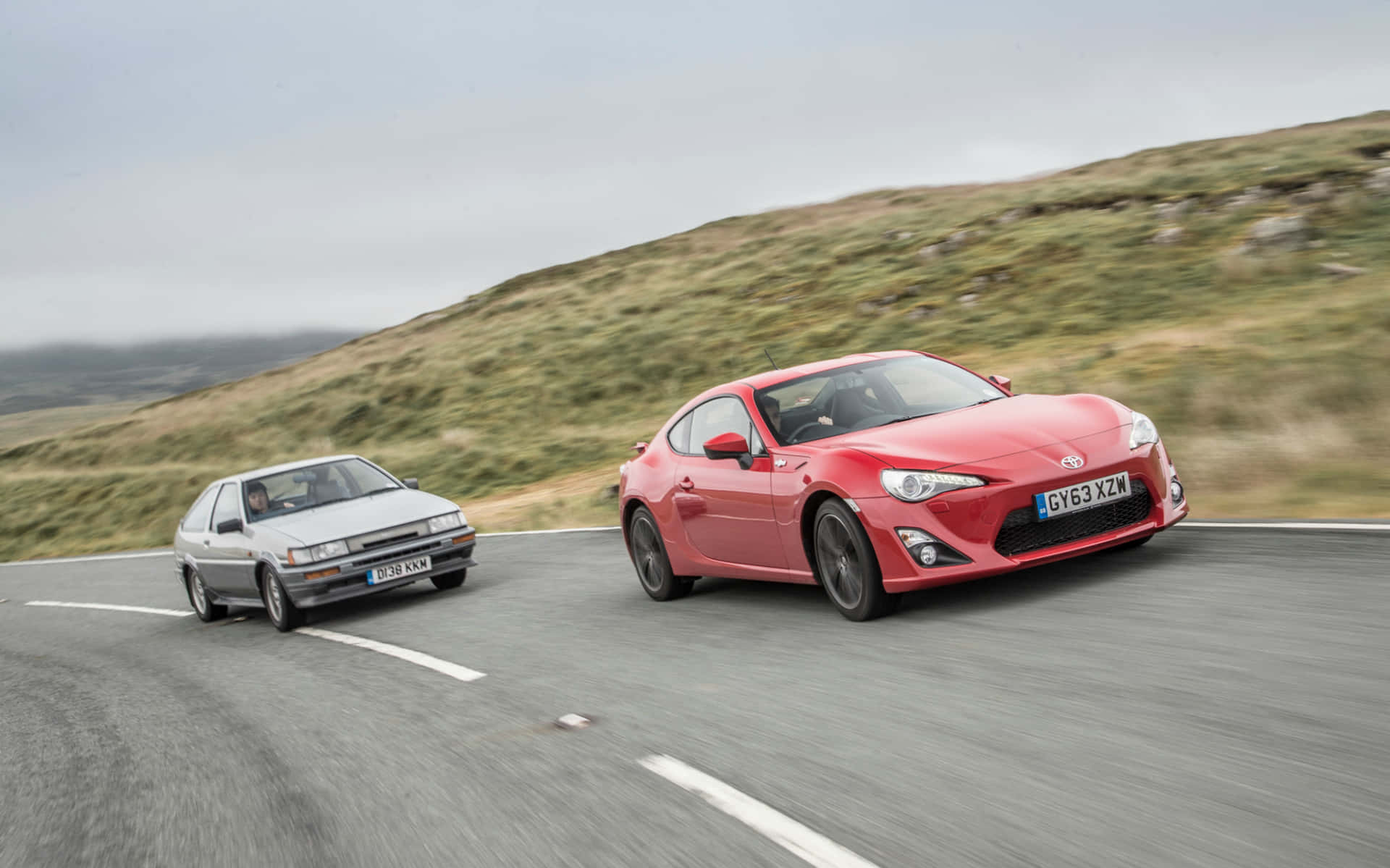 Two Cars Are Driving Down A Road Background