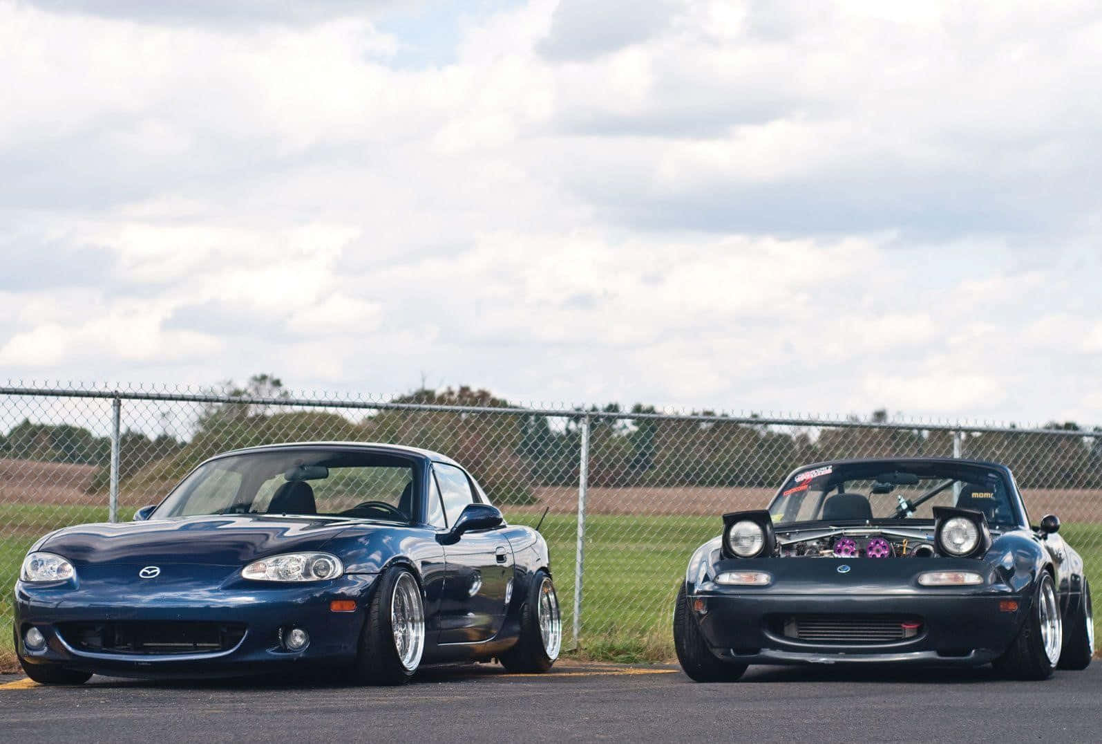 Two Cars Parked Next To Each Other On A Race Track