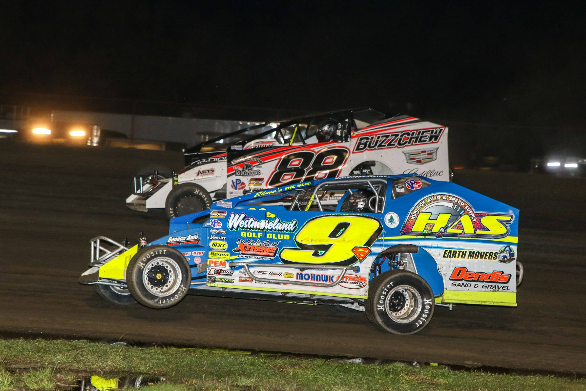 Two Dirt Race Cars Racing On A Dirt Track At Night Background