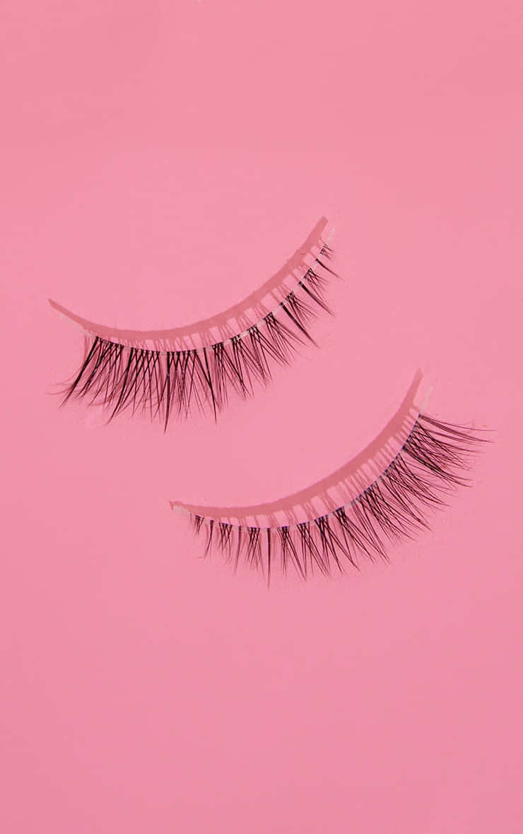 Two False Eyelashes On A Pink Background Background