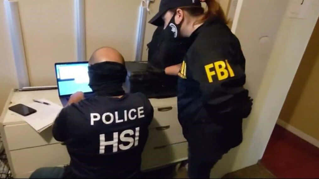 Two Fbi Agents Working On A Laptop Background