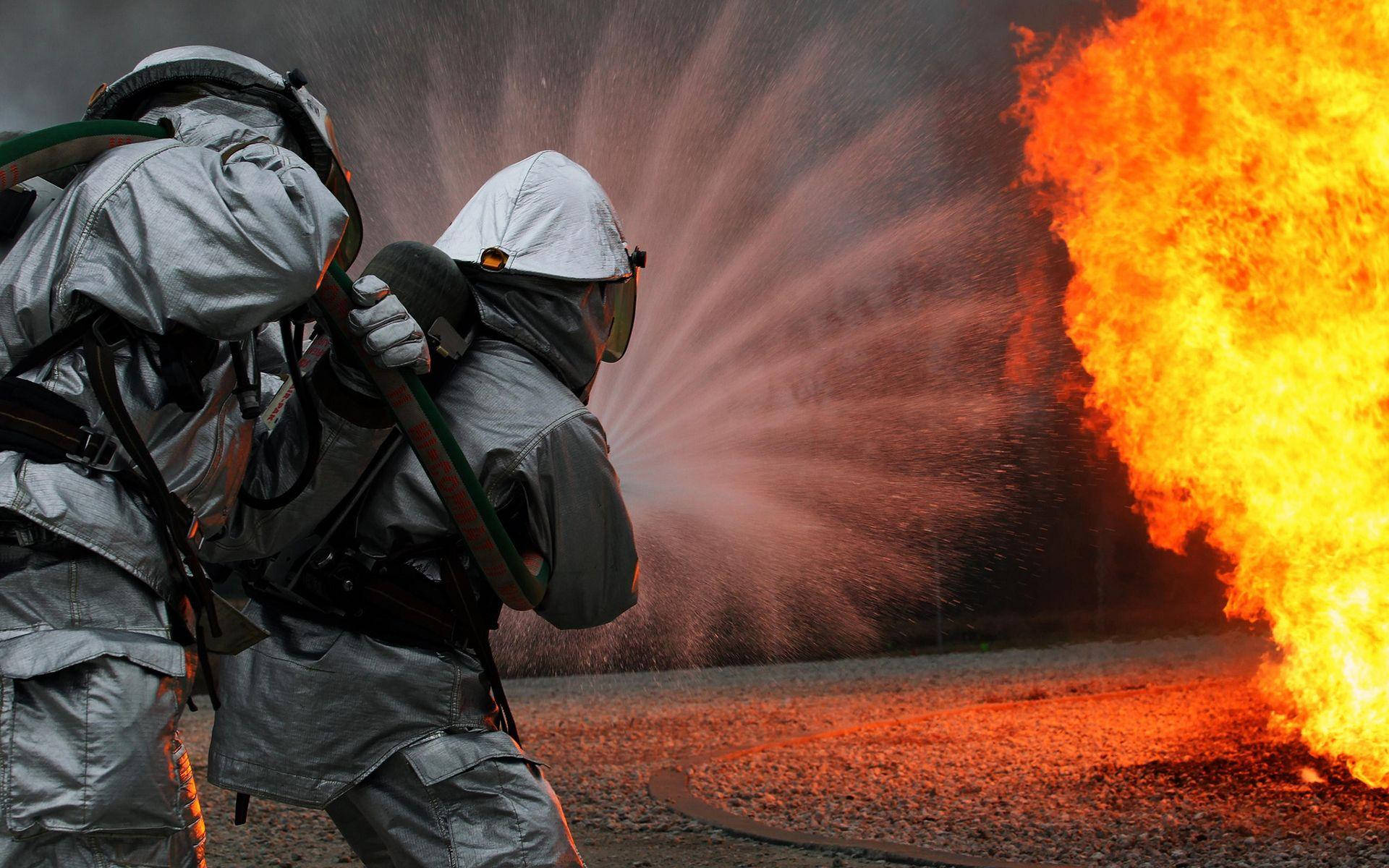 Two Firefighters Applying Water To Fire Background