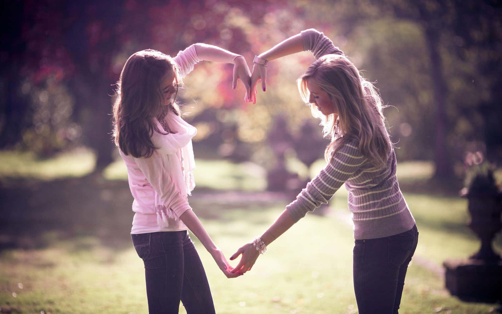 Two Girls Holding Hands In A Heart Shape Background