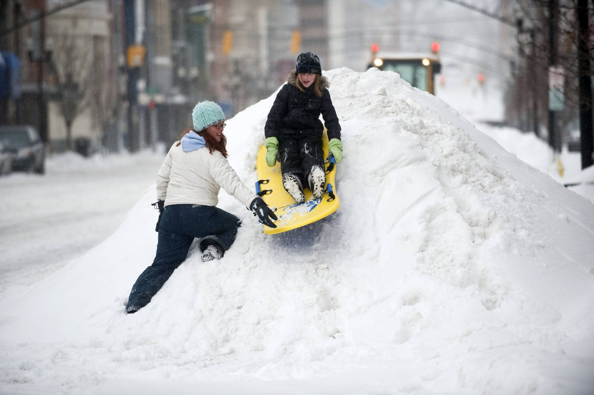 Two Girls Sledding On The Snow Background