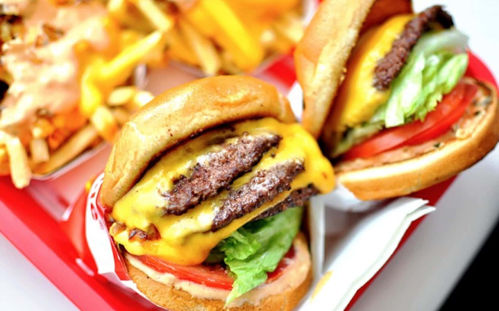 Two Hamburgers And Fries Are On A Red Tray Background