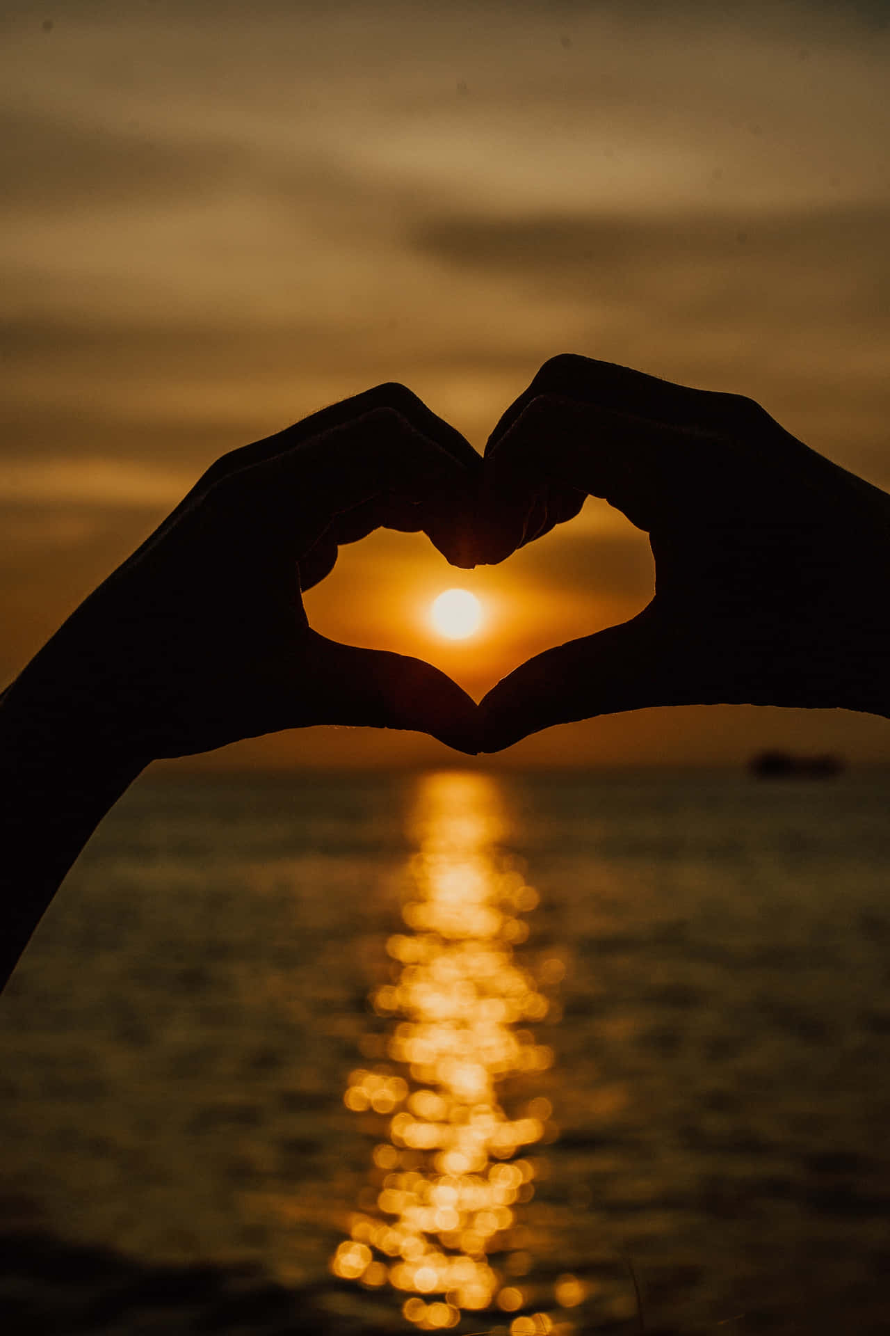 Two Hands Making A Heart Shape At Sunset Background