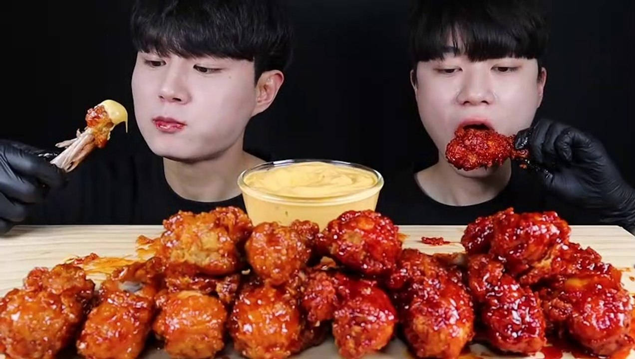 Two Men Are Eating A Plate Of Chicken Wings