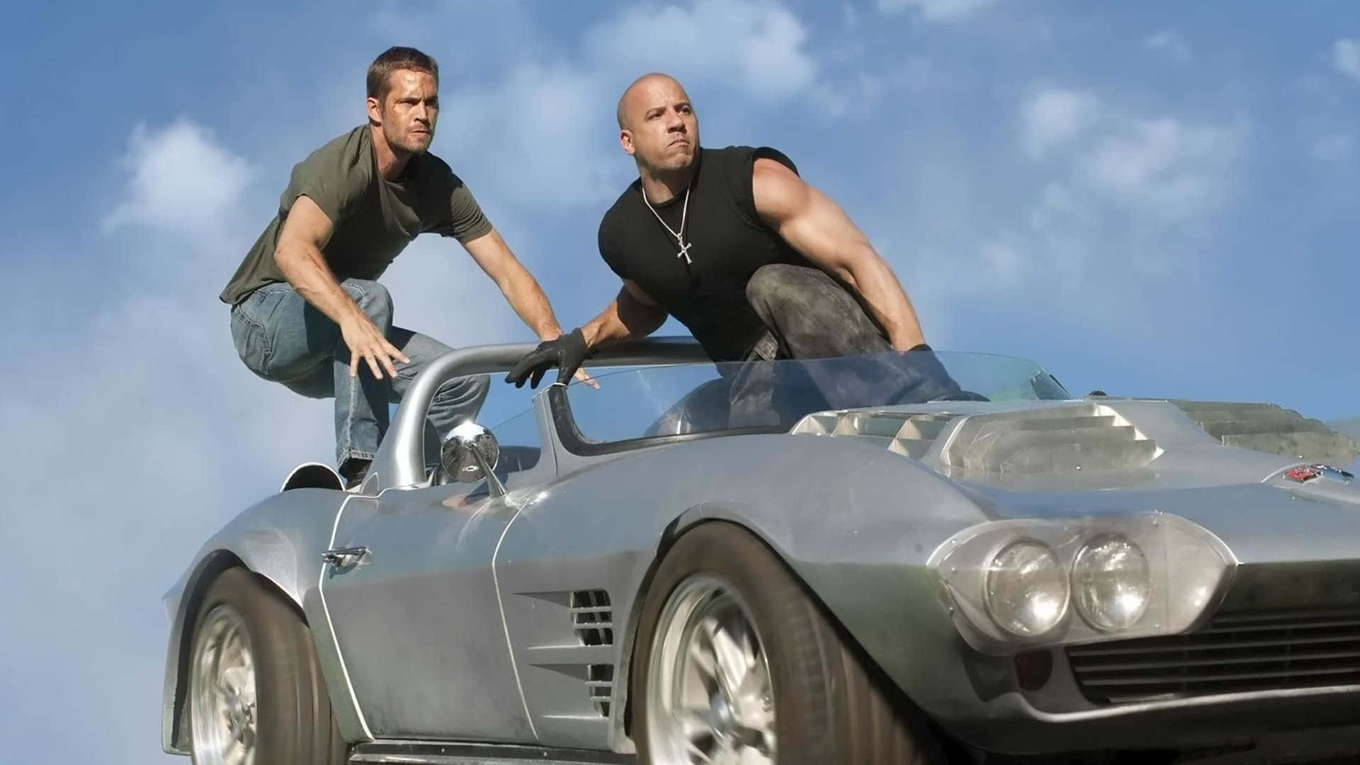 Two Men Are Standing On Top Of A Silver Car Background