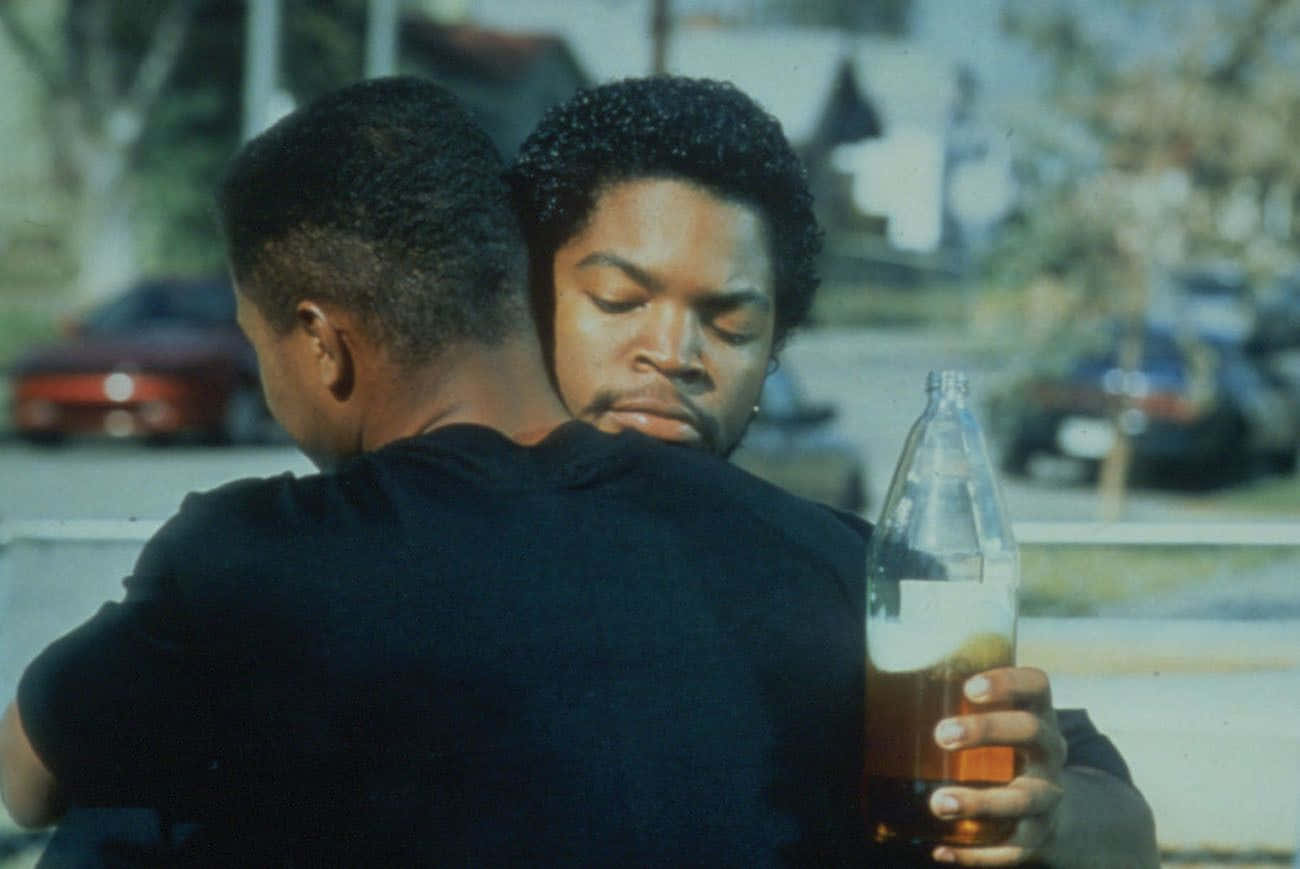 Two Men Hugging Each Other In Front Of A Building Background