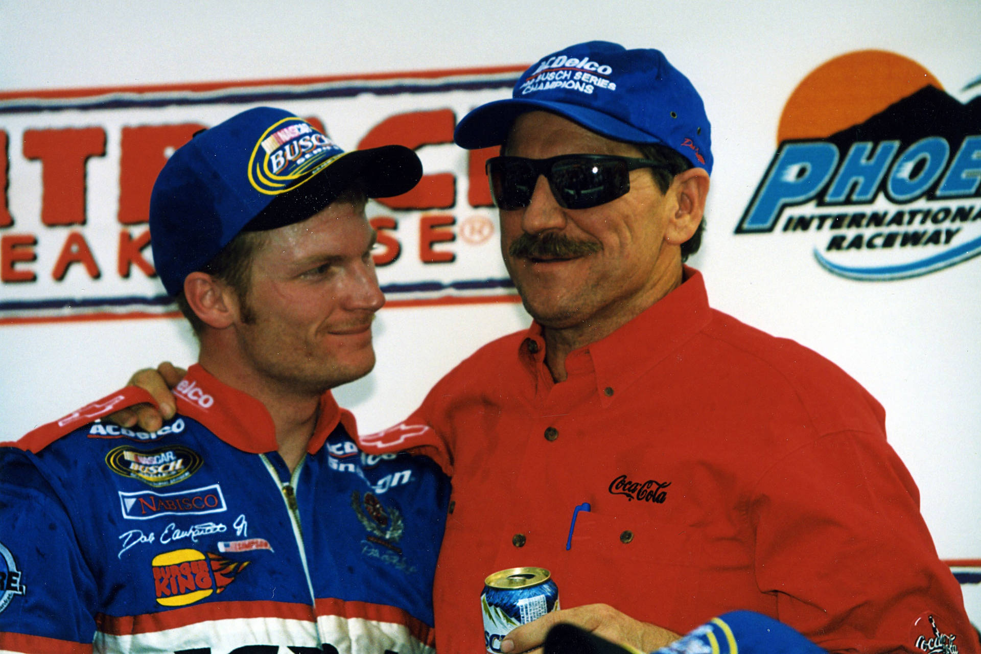 Two Men In Nascar Shirts And Hats Standing Next To Each Other