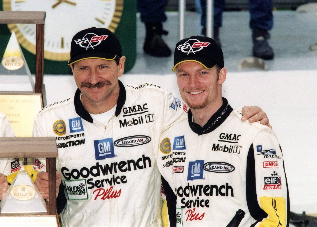 Two Men In Nascar Uniforms Standing Next To Each Other Background