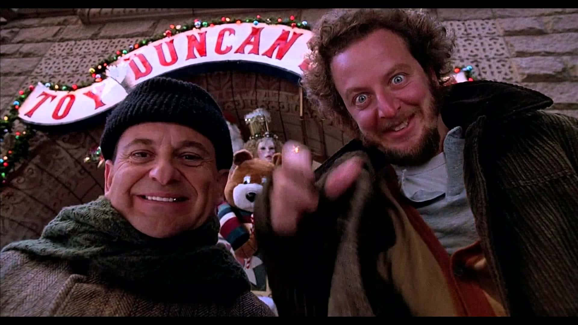 Two Men In Winter Clothes Standing Next To A Christmas Tree Background