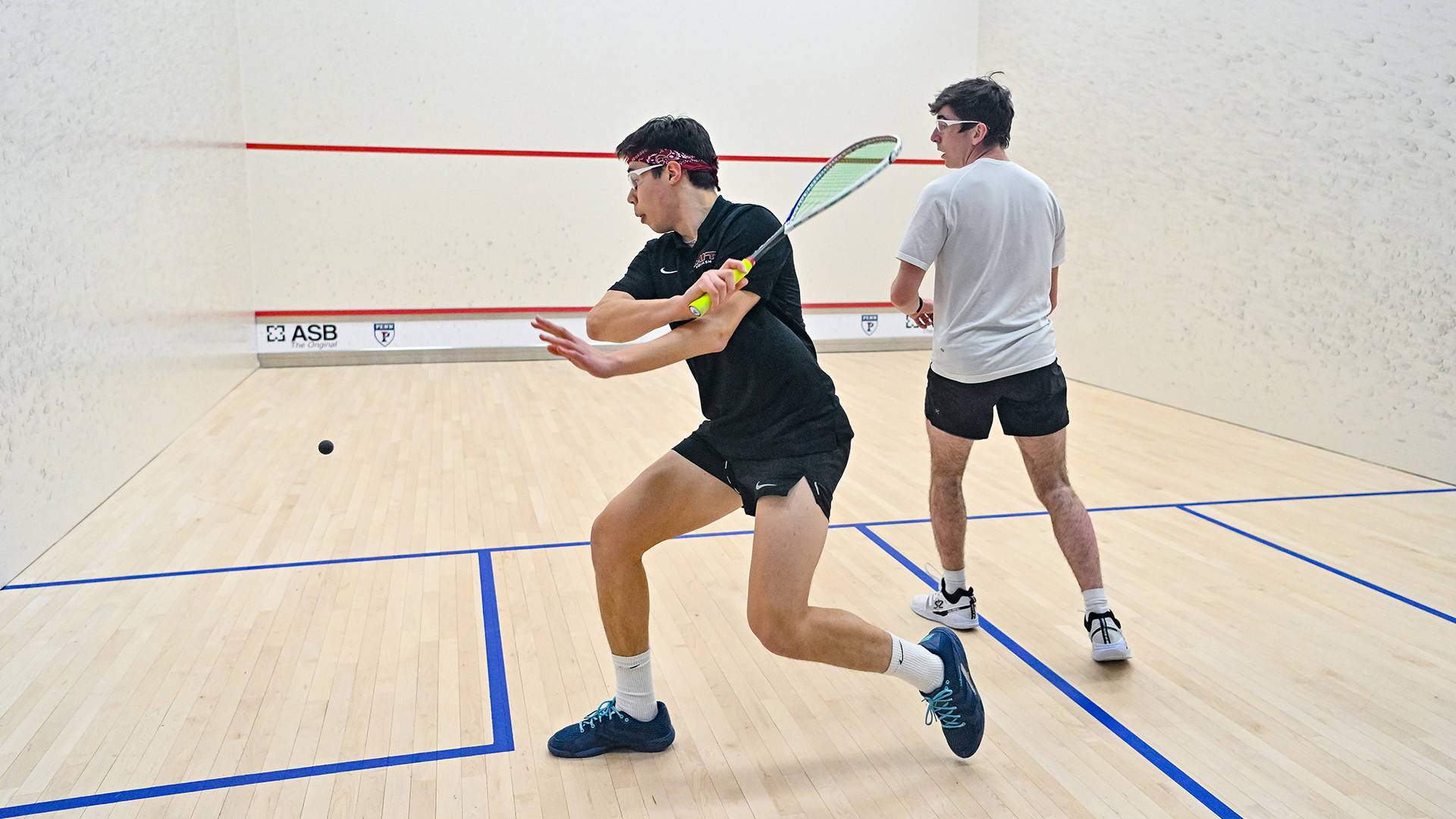 Two Men Looking At Squash Ball