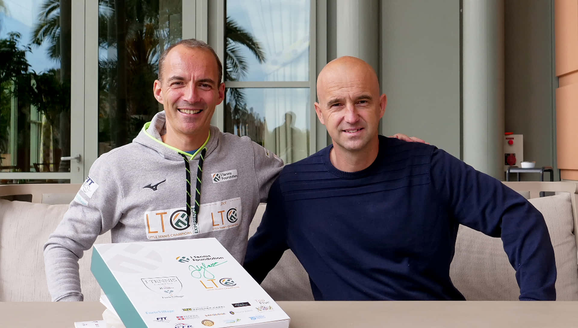 Two Men Smiling With Award Certificate Outdoors