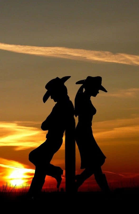 Two Silhouettes Of A Couple Walking In The Sunset Background