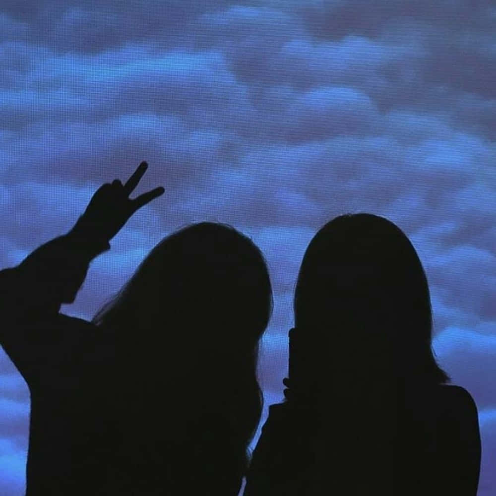 Two Silhouettes Of Women Holding Up Their Hands In Front Of A Blue Sky Background
