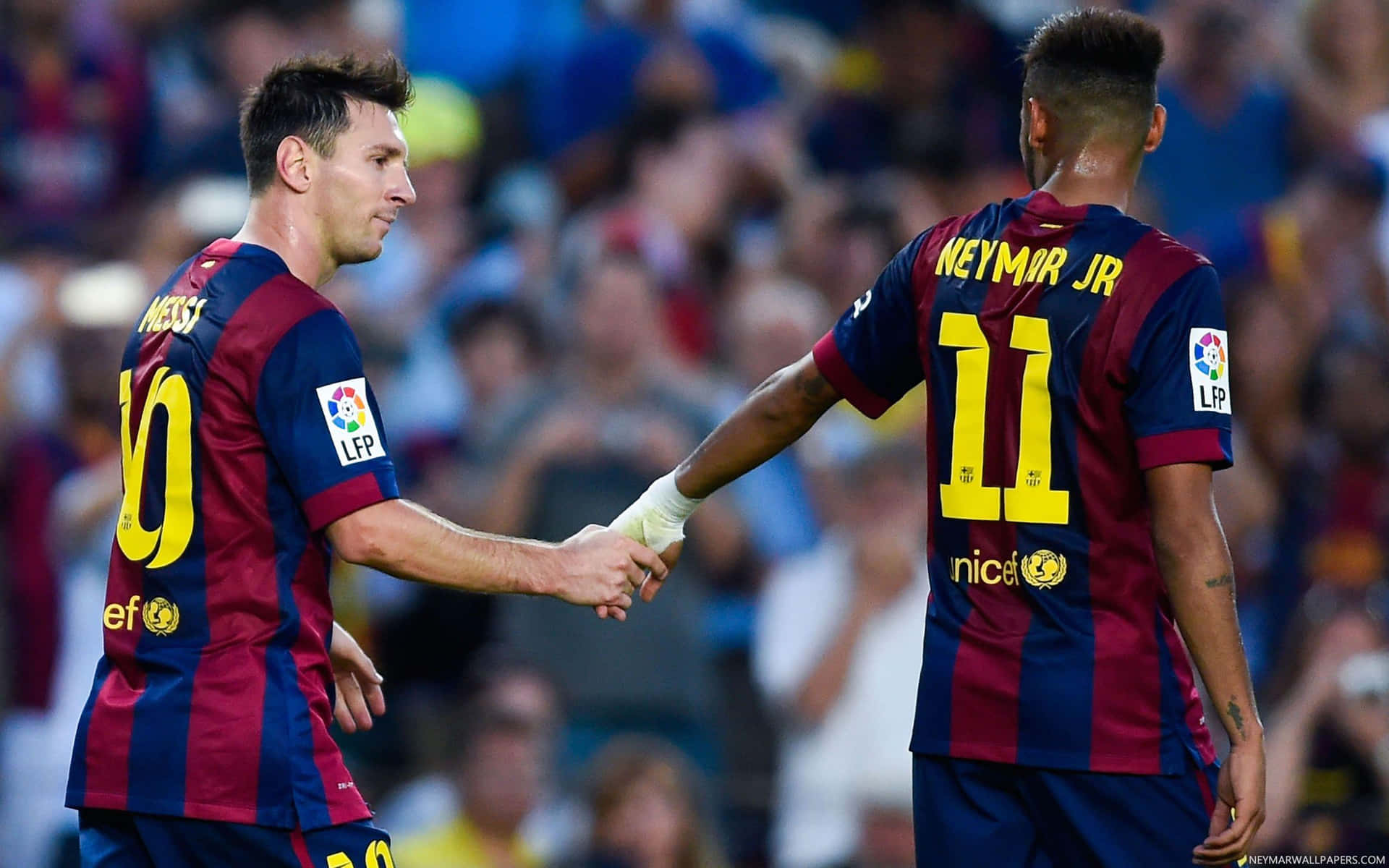 Two Soccer Players Shaking Hands In Front Of A Crowd Background