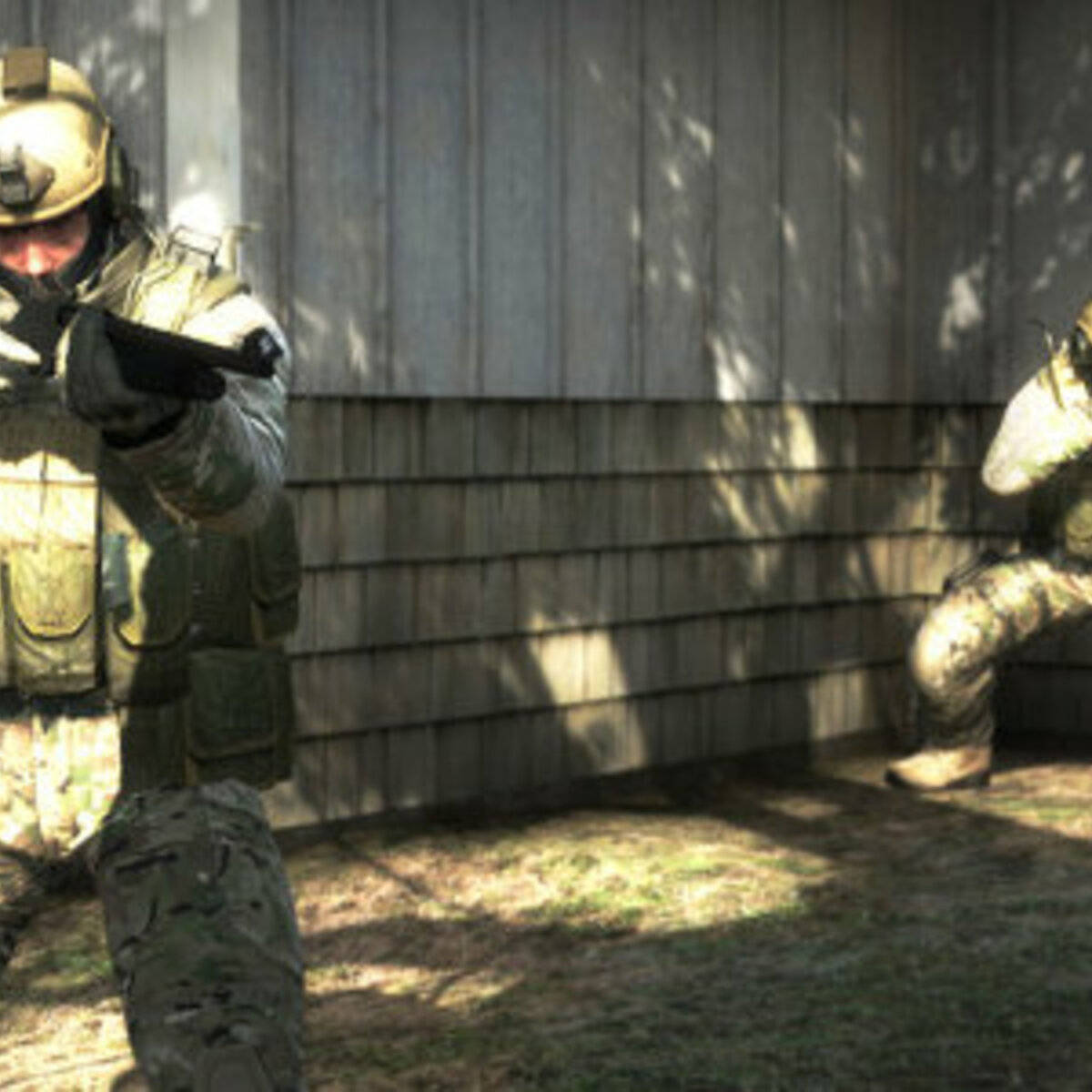 Two Soldiers In Camouflage Are Standing In Front Of A House Background