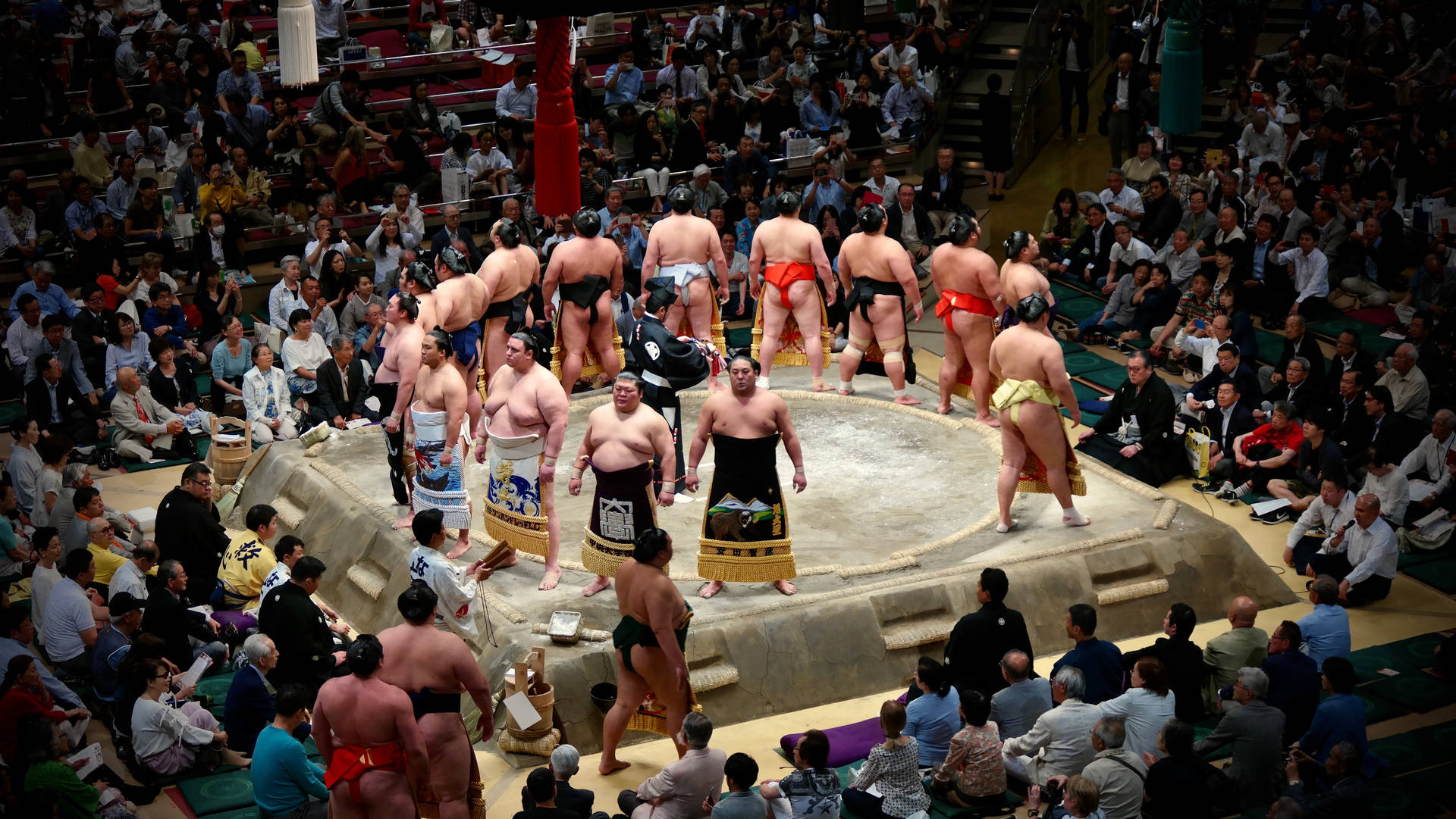 Two Sumo Wrestlers Clash In A Traditional Japanese Arena Background