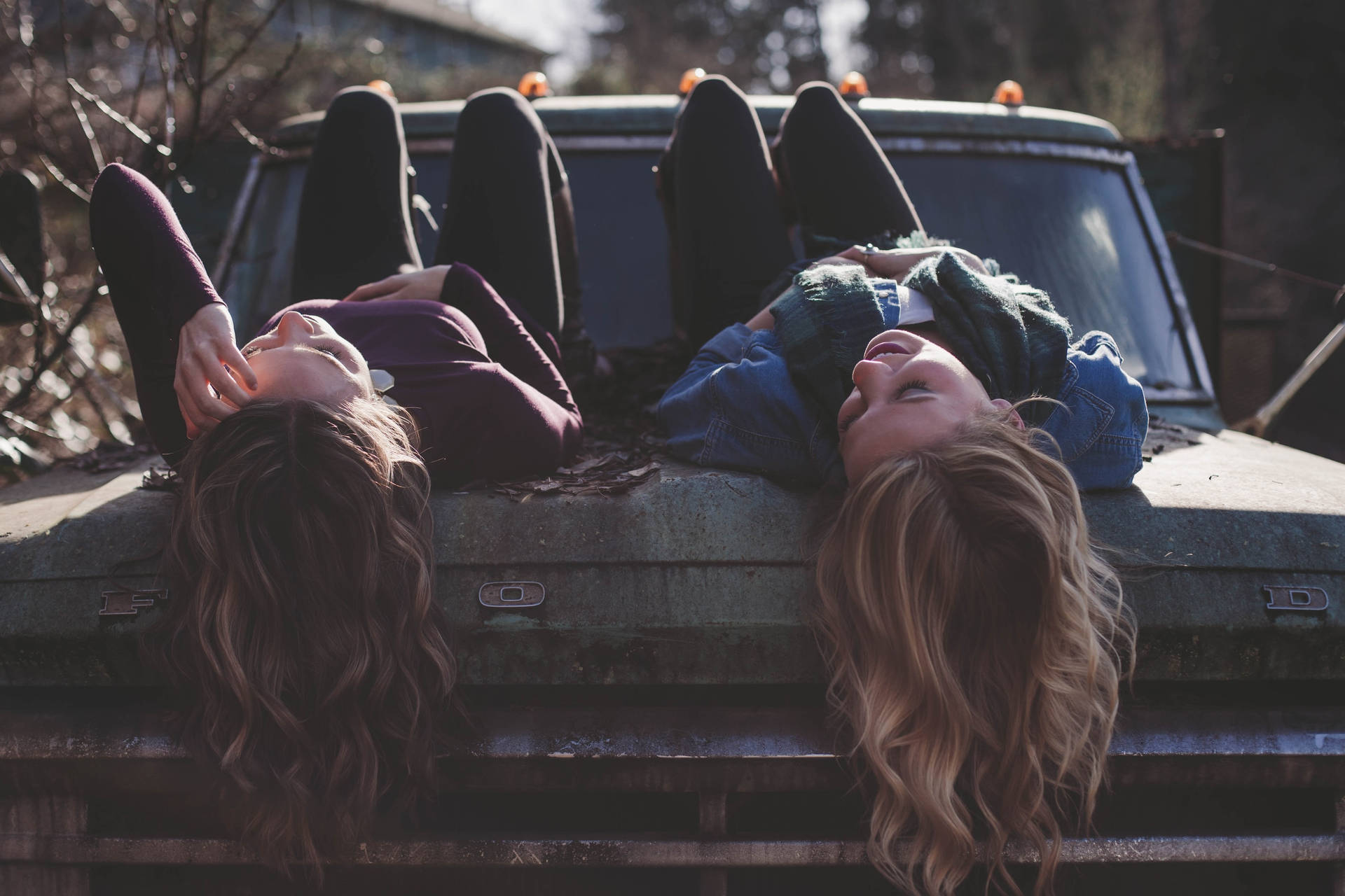 Two Teenage Girls Lying On The Car Background