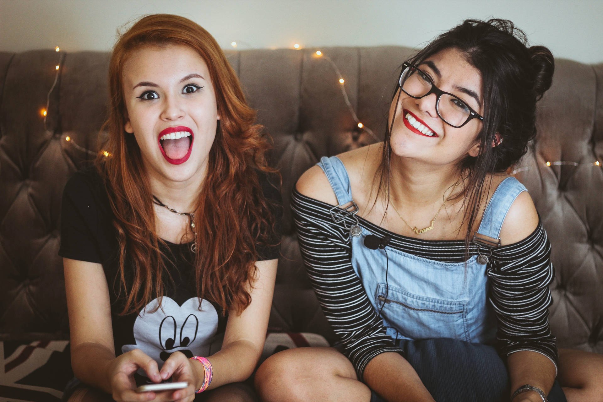 Two Teenage Girls Sitting At The Sofa Background