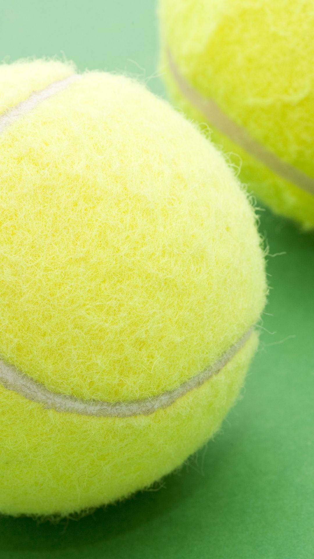 Two Tennis Balls On A Green Surface Background