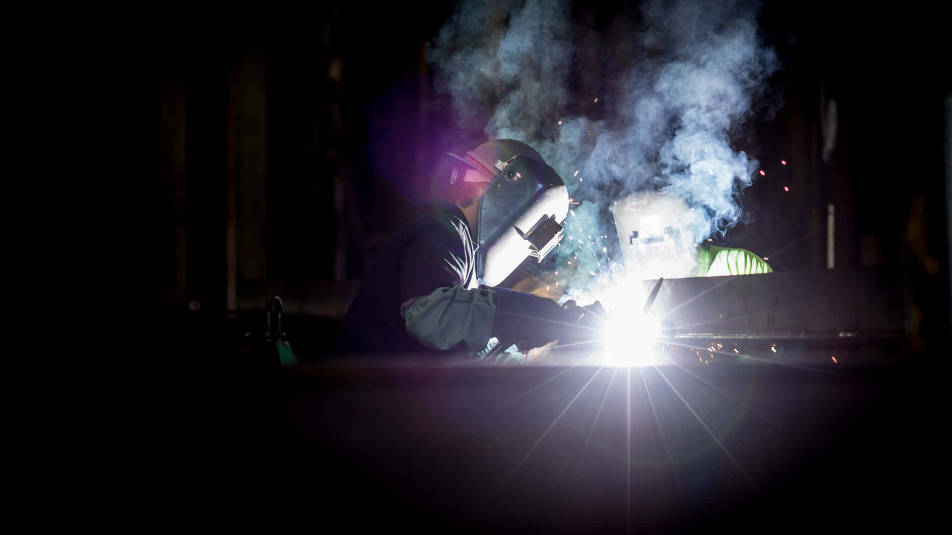 Two Welders Working On A Metal Piece Background