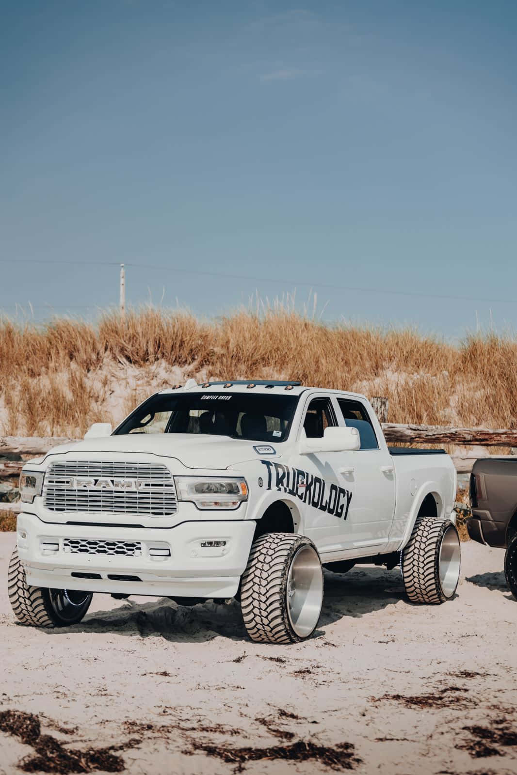 Two White Trucks Parked On The Beach Background