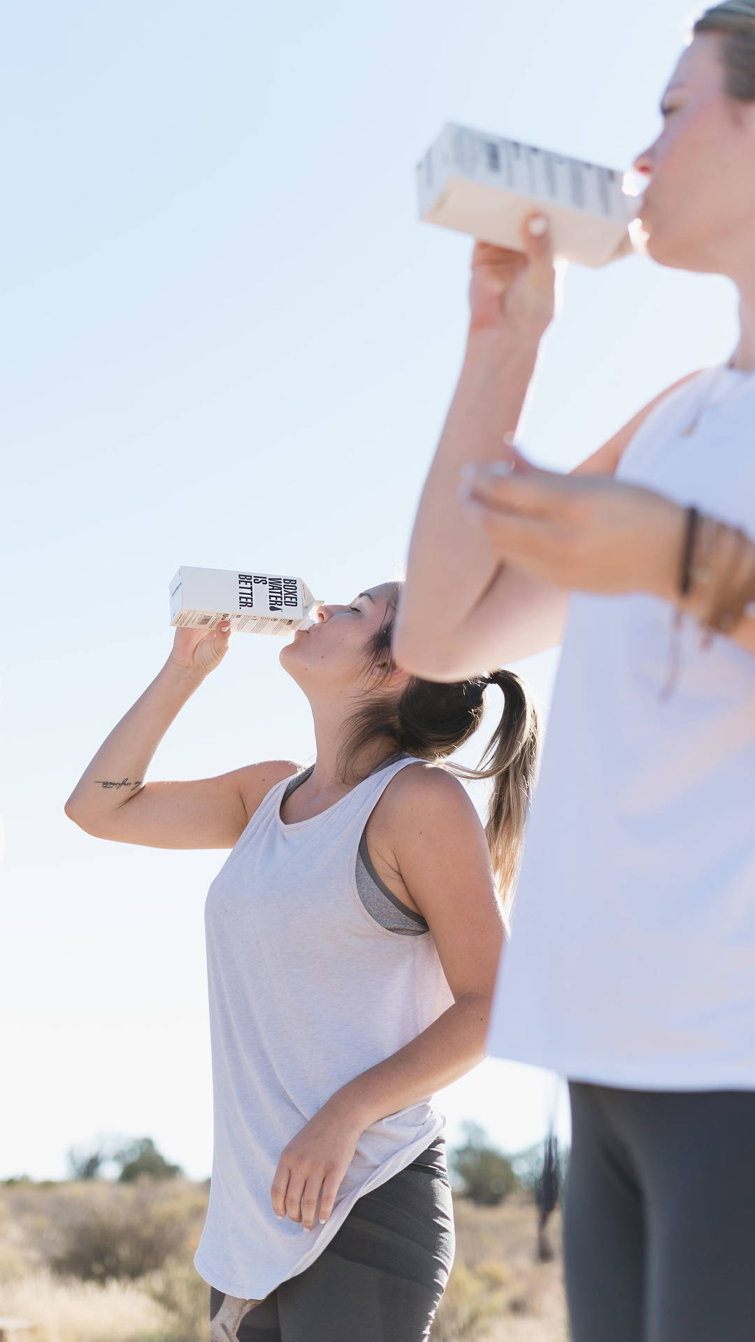 Two Women Drinking Water From Box Background