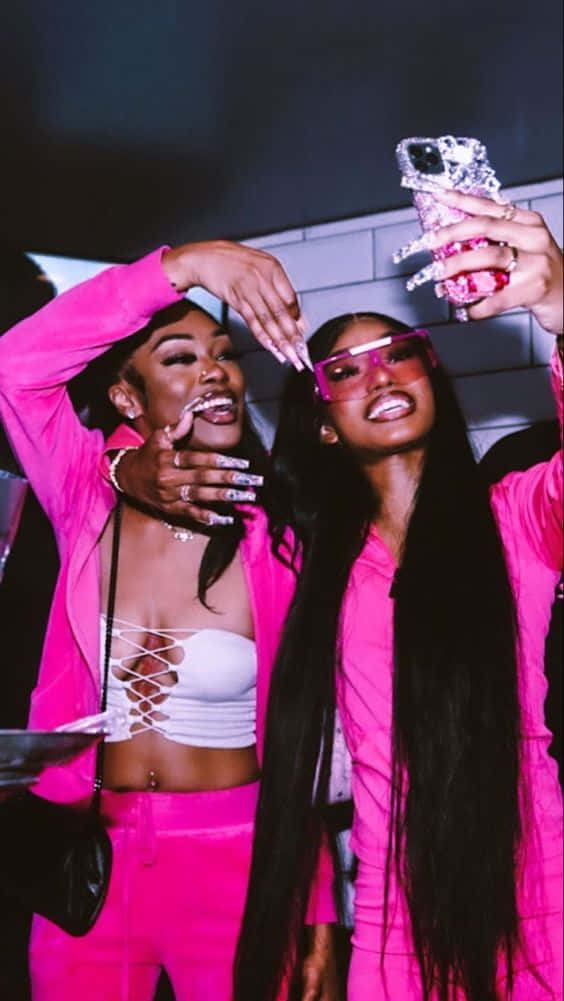 Two Women In Pink Outfits Taking A Selfie Background