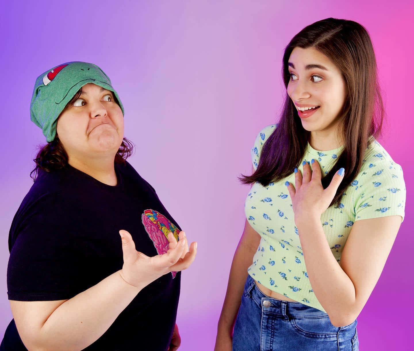 Two Women Standing Next To Each Other With A Pink Background Background