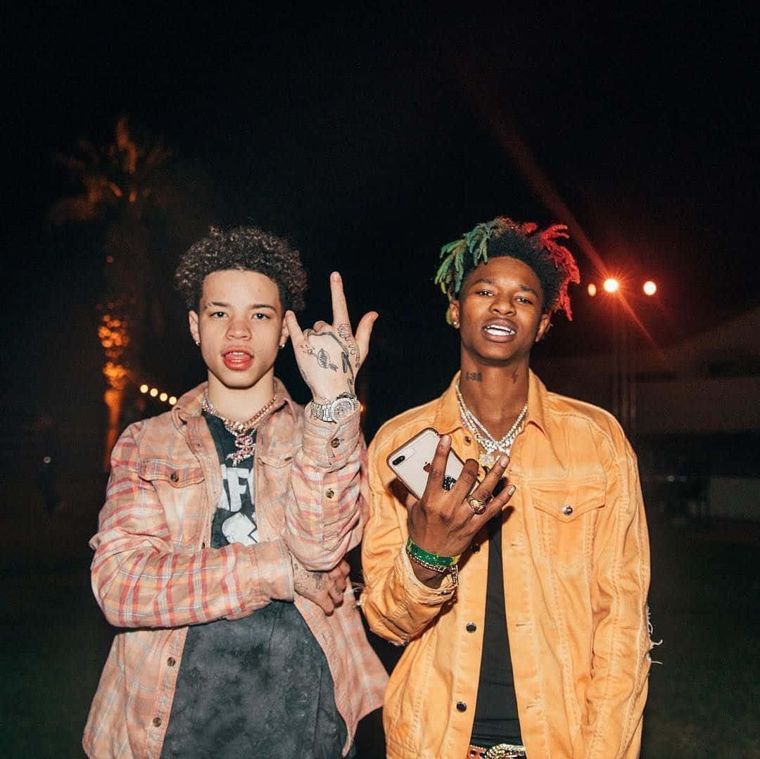 Two Young Men Standing Next To Each Other At Night Background