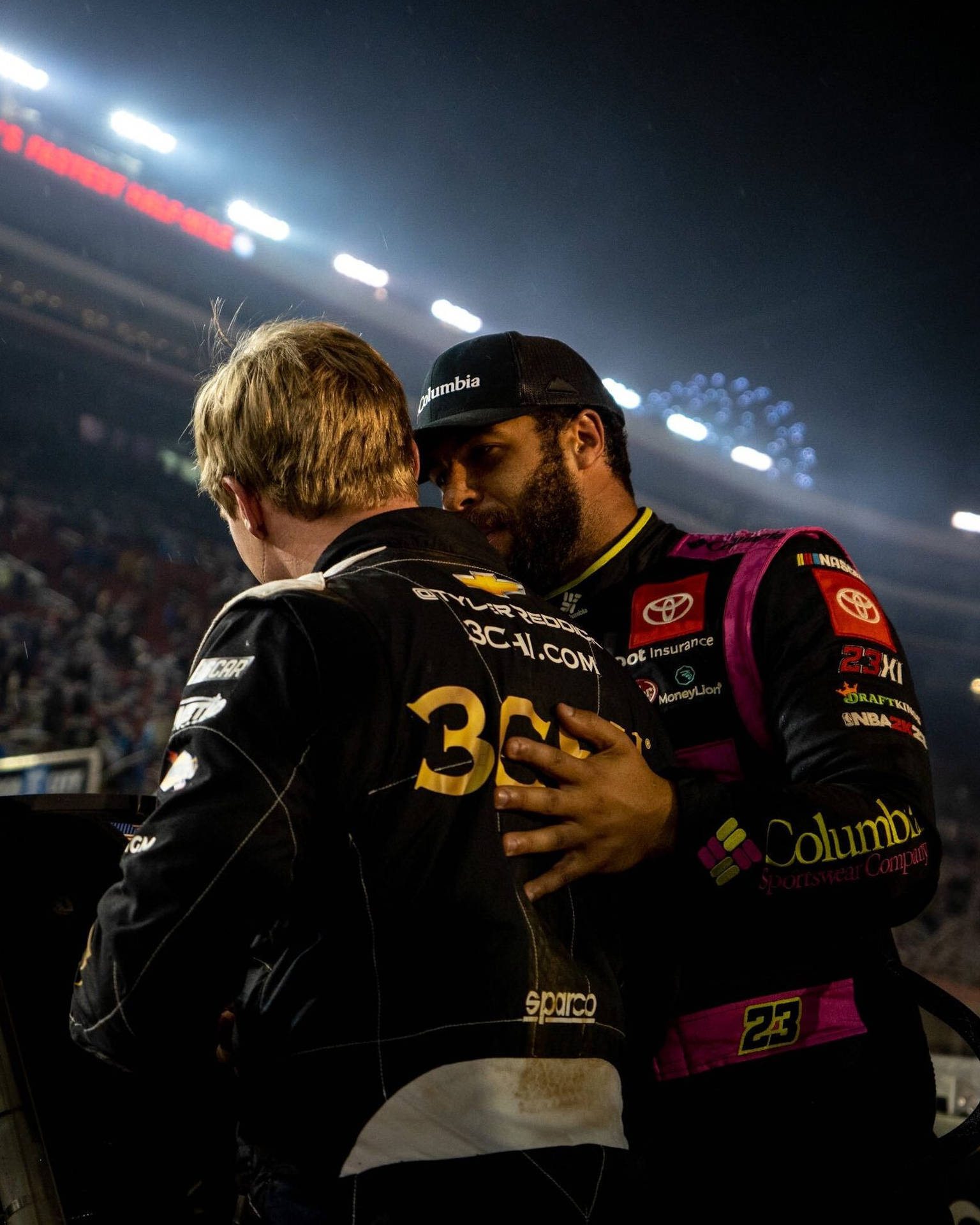 Tyler Reddick And A Fellow Driver In High-intensity Race Background