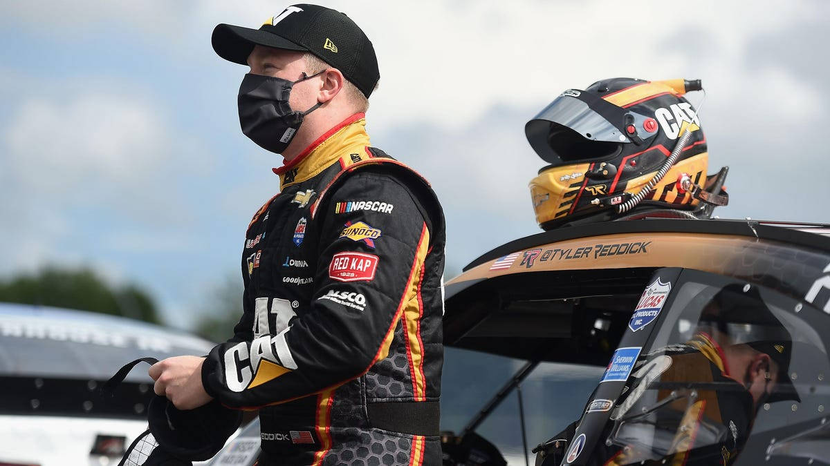 Tyler Reddick With Helmet Preparing To Speed In His Racing Car Background