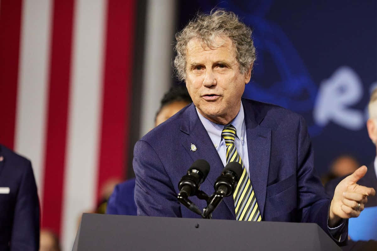 U.s. Senator Sherrod Brown Speaking At Podium Background