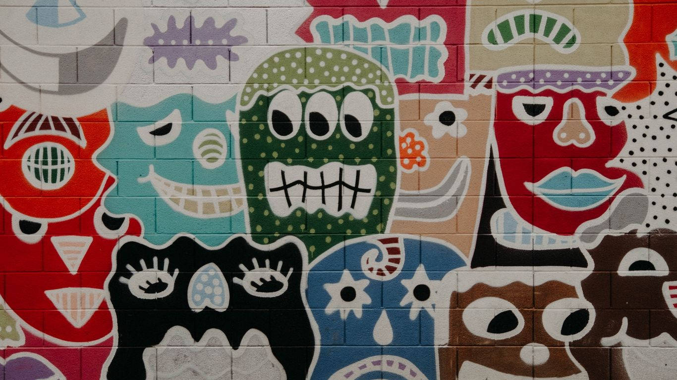 Unleashing Creativity With Colorful Graffiti Monster Faces On A Laptop Background