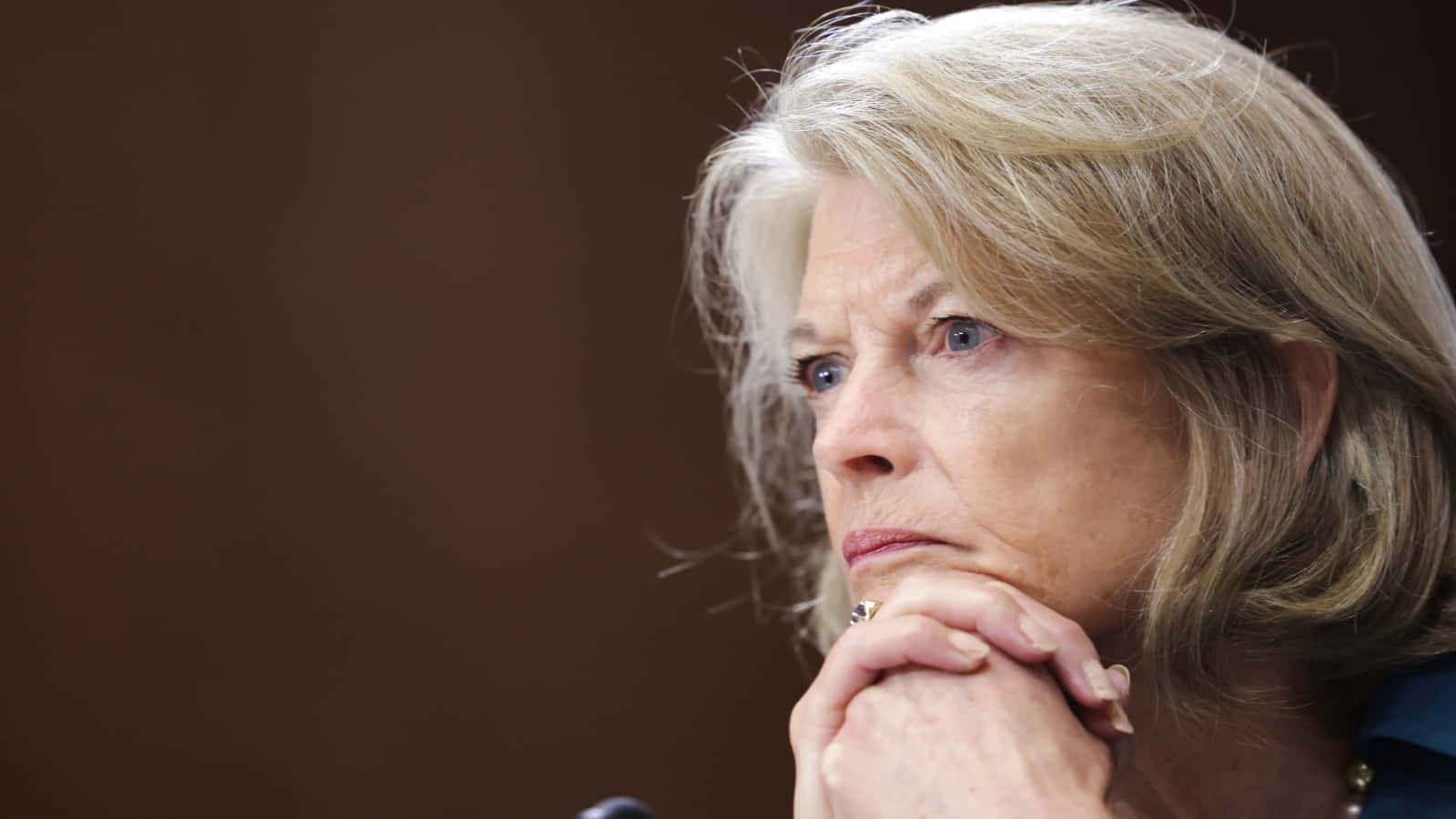 Us Senator Lisa Murkowski In A Deep Contemplative Gesture Background