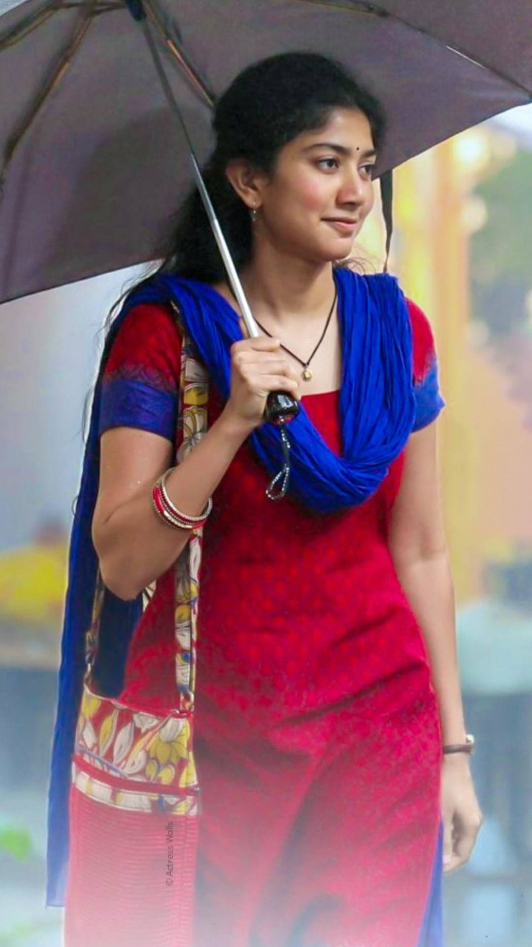 Versatile Actress Sai Pallavi Bracing The Rain With An Umbrella Background