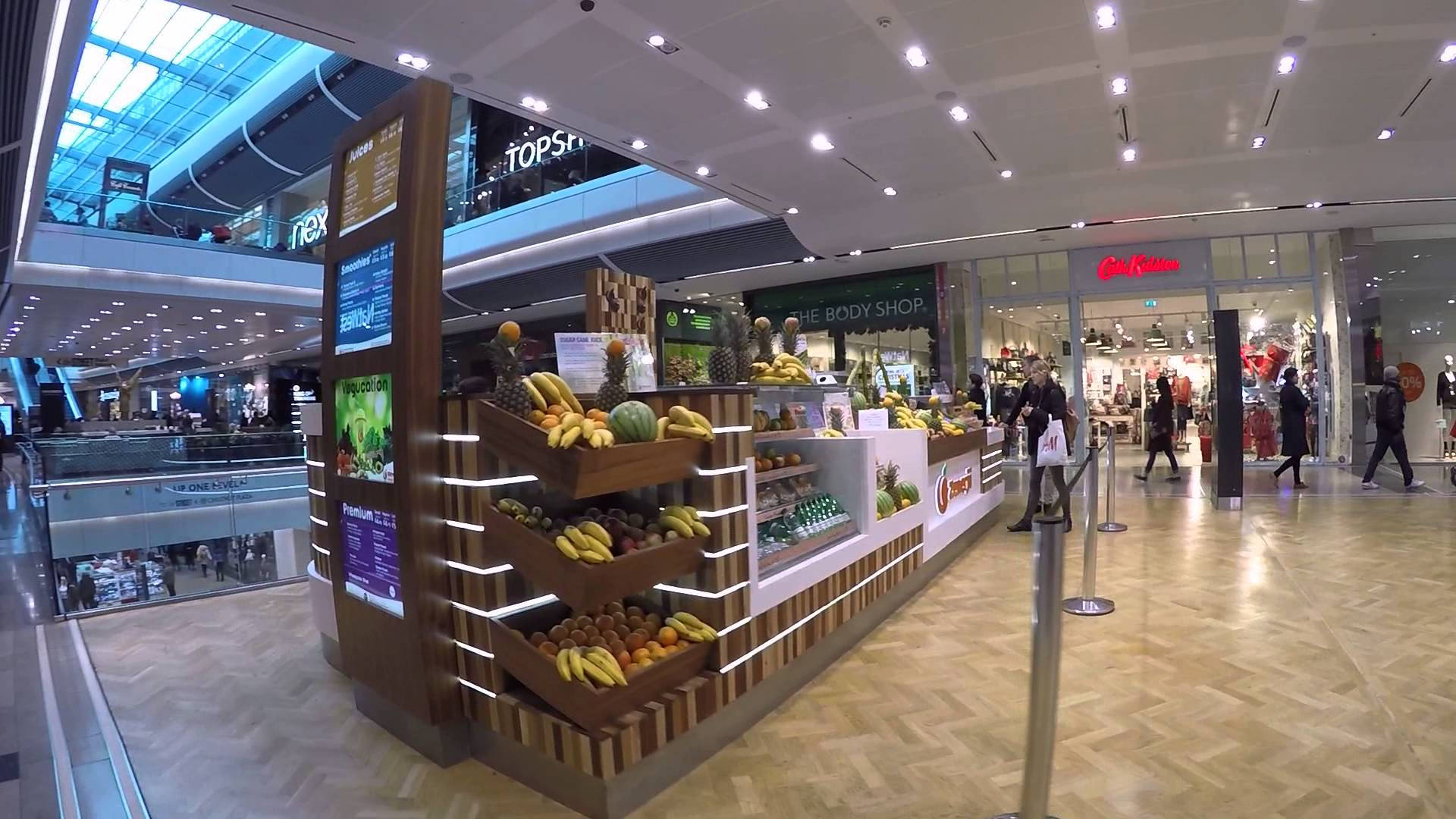 Vibrant Fruit Stand In A Bustling Mall Background