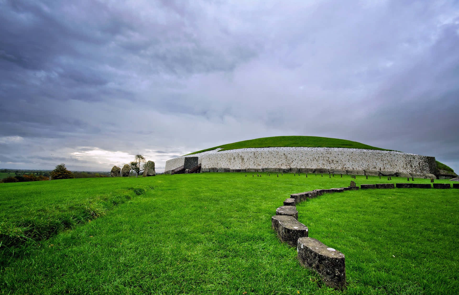 Vibrant Newgrange Passage Tomb With Stormy Cloud Background