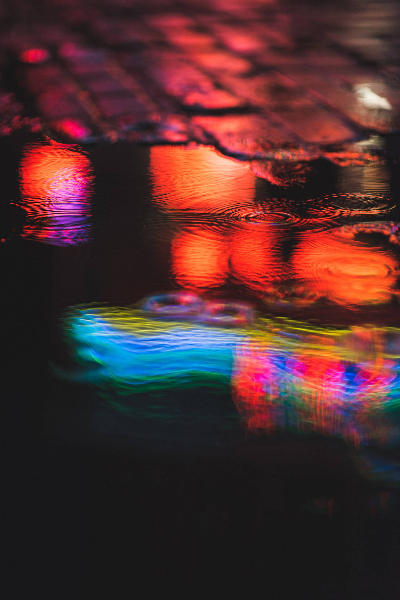 Vibrant Night Colors Reflecting On An Urban Puddle Background
