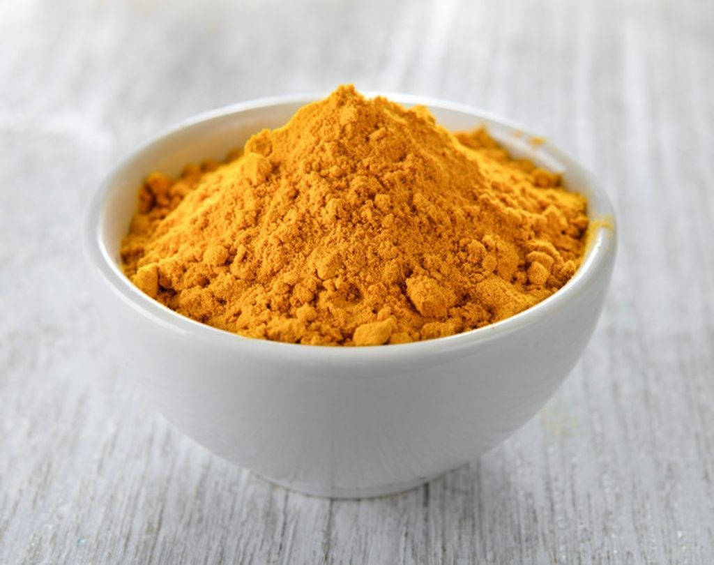 Vibrant Turmeric Powder In A Simple White Bowl Background