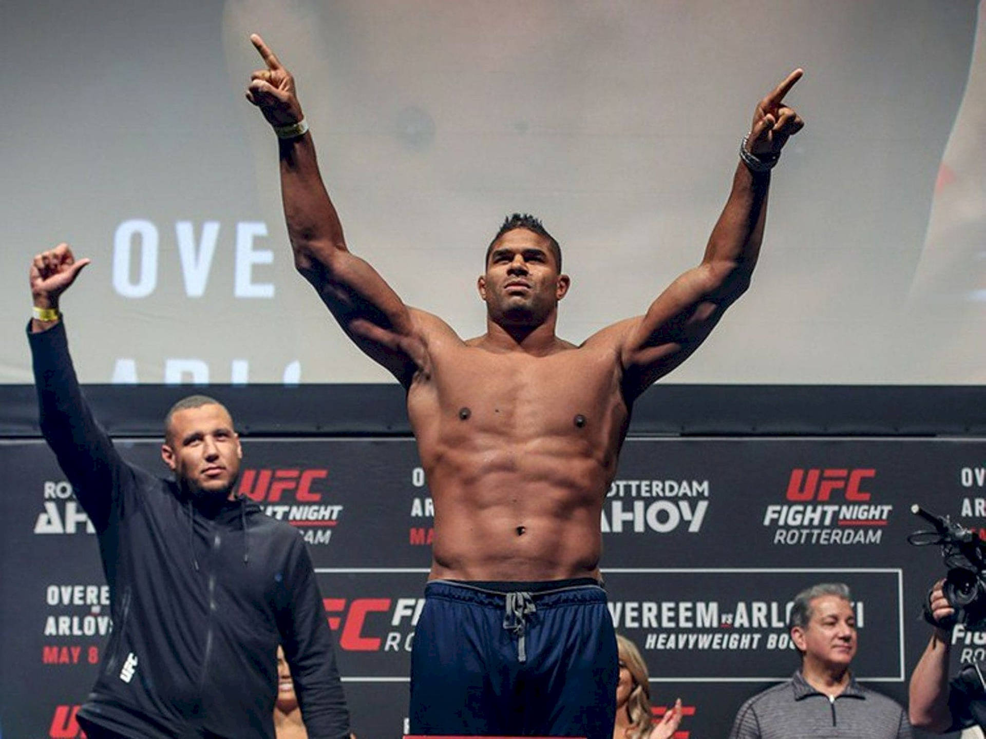 Victorious Alistair Overeem Raising His Hands High Background