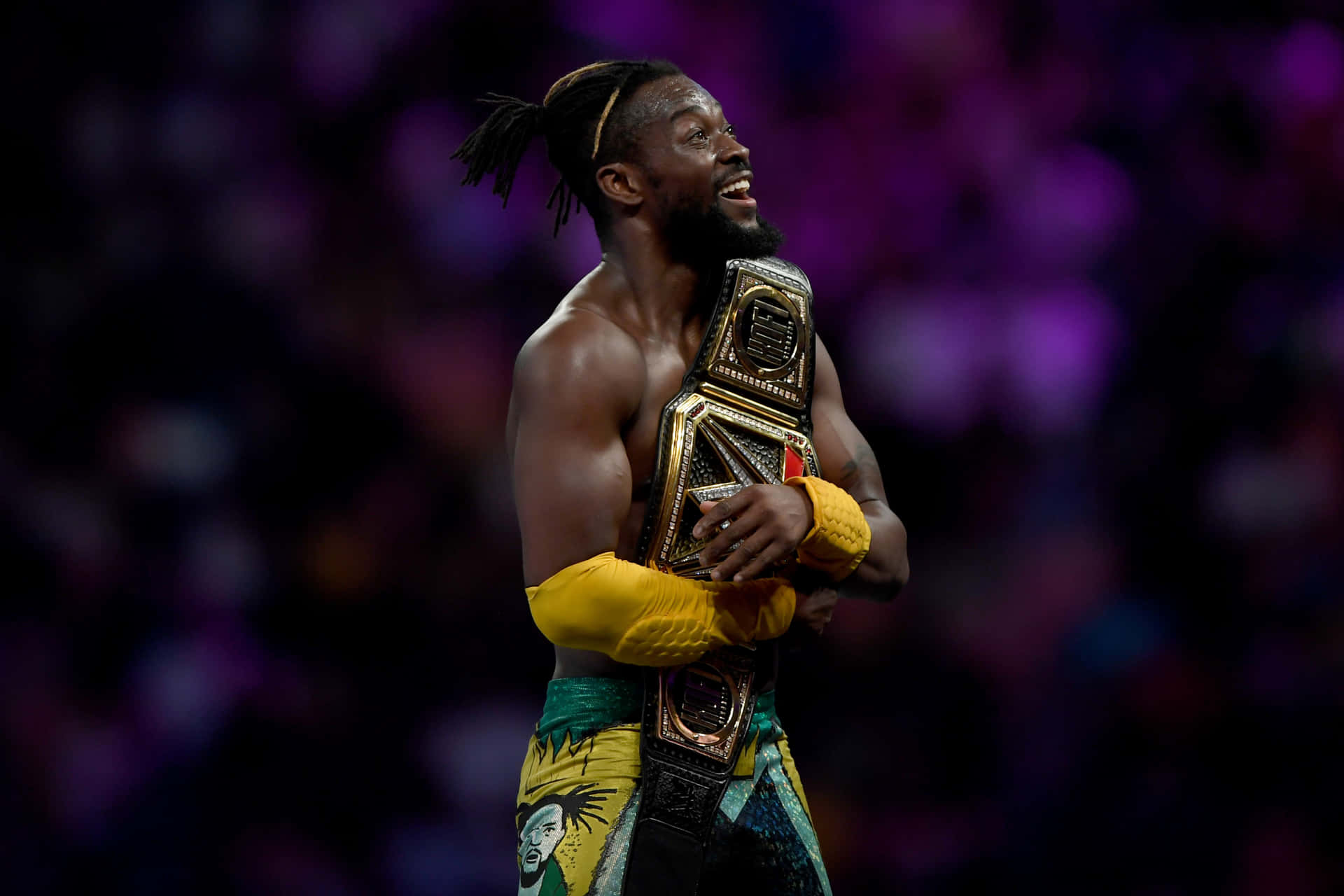 Victorious Kofi Kingston Hugging His Wwe Belt Background